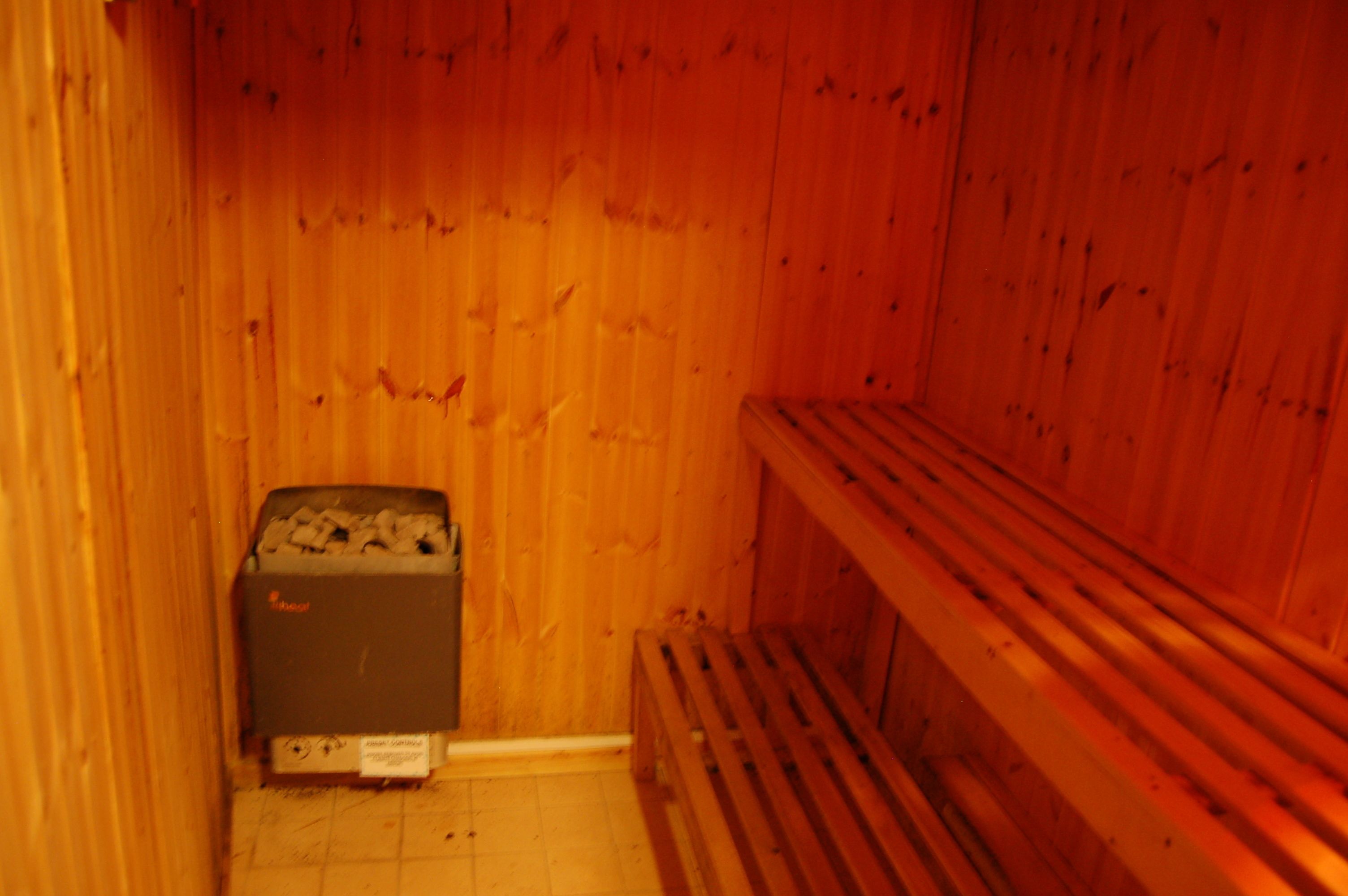 Una sala de sauna con paredes de madera, un banco y un calentador.