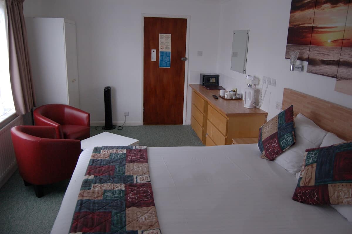 A hotel room with a bed, a desk with a computer, a chair, and a wardrobe.