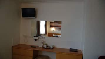 A bathroom with a wooden vanity, a mirror, a television mounted above the mirror, and a towel rack.