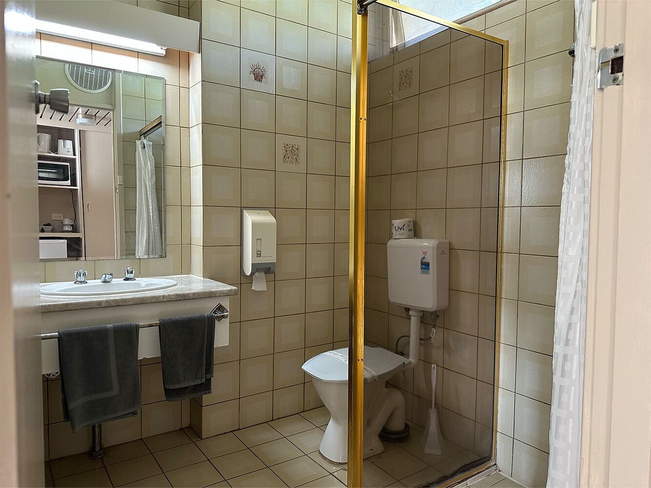 Un baño con cabina de ducha, lavabo, inodoro y espejo.