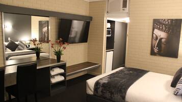 Een hotelkamer met een bed, een bureau met stoel, een flatscreen-tv, een magnetron, en een grote Boeddhabele afkomstig van de muur.