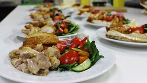 Uma mesa de buffet com diversos pratos, incluindo saladas, carnes e pão.