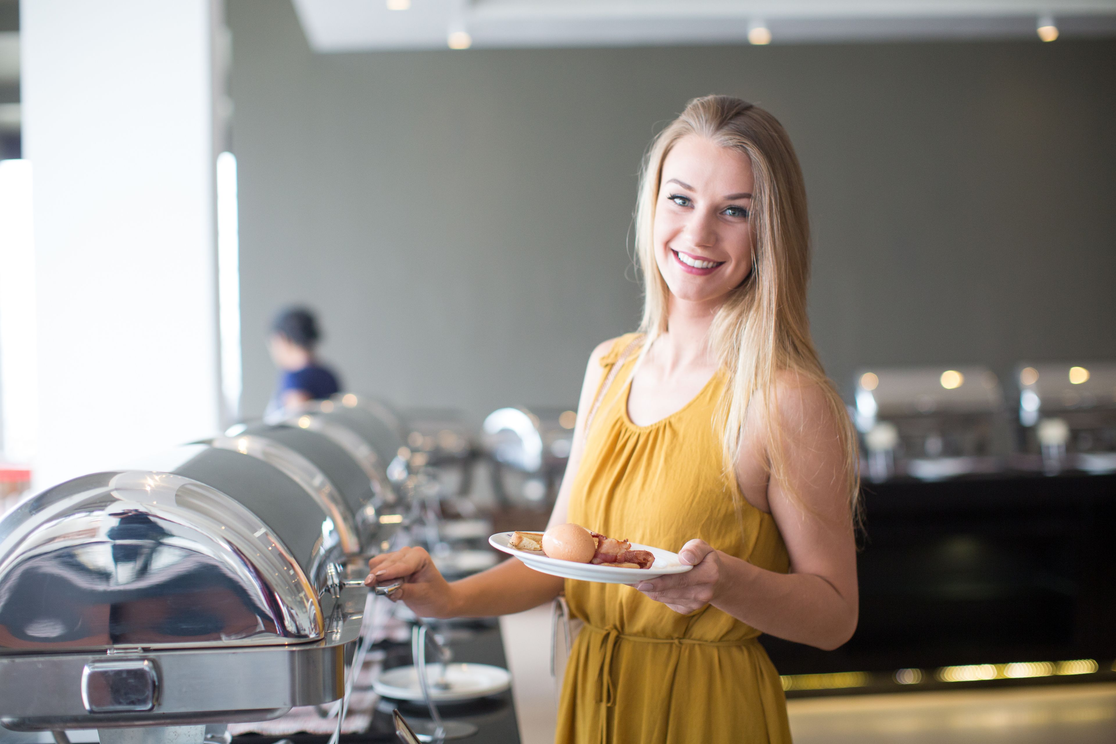 A buffet setup with covered food stations and a person serving food.