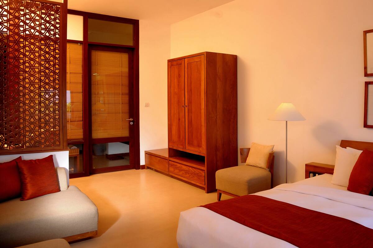 Ein Hotelzimmer mit Bett, Sofa, Kleiderschrank und einer Stehlampe.