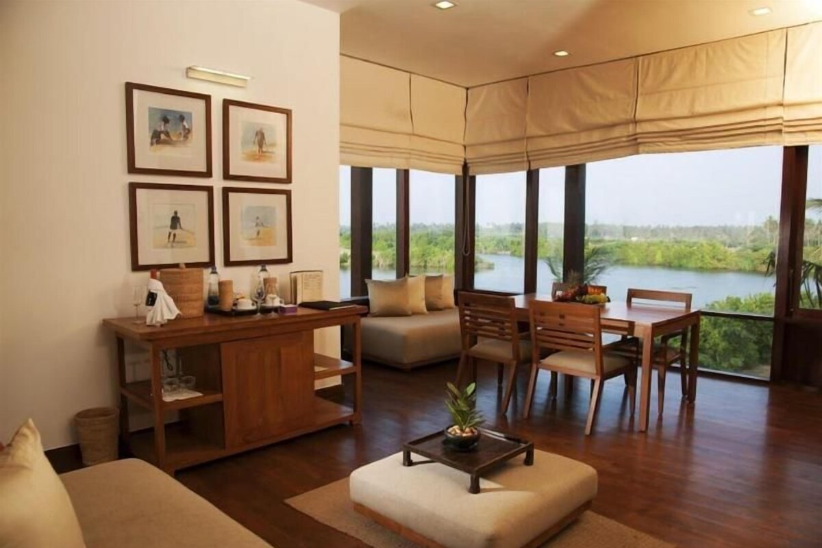 A spacious living area with a sofa, a dining table, and chairs, a small coffee table, and a view of a body of water.