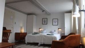 Une chambre d’hôtel comprenant un lit, deux tables de chevet, une chaise, un bureau et une lampe.