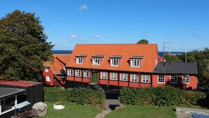 Un bâtiment rouge à deux étages, doté d’un toit en pente, d’une porte verte et de nombreuses fenêtres.