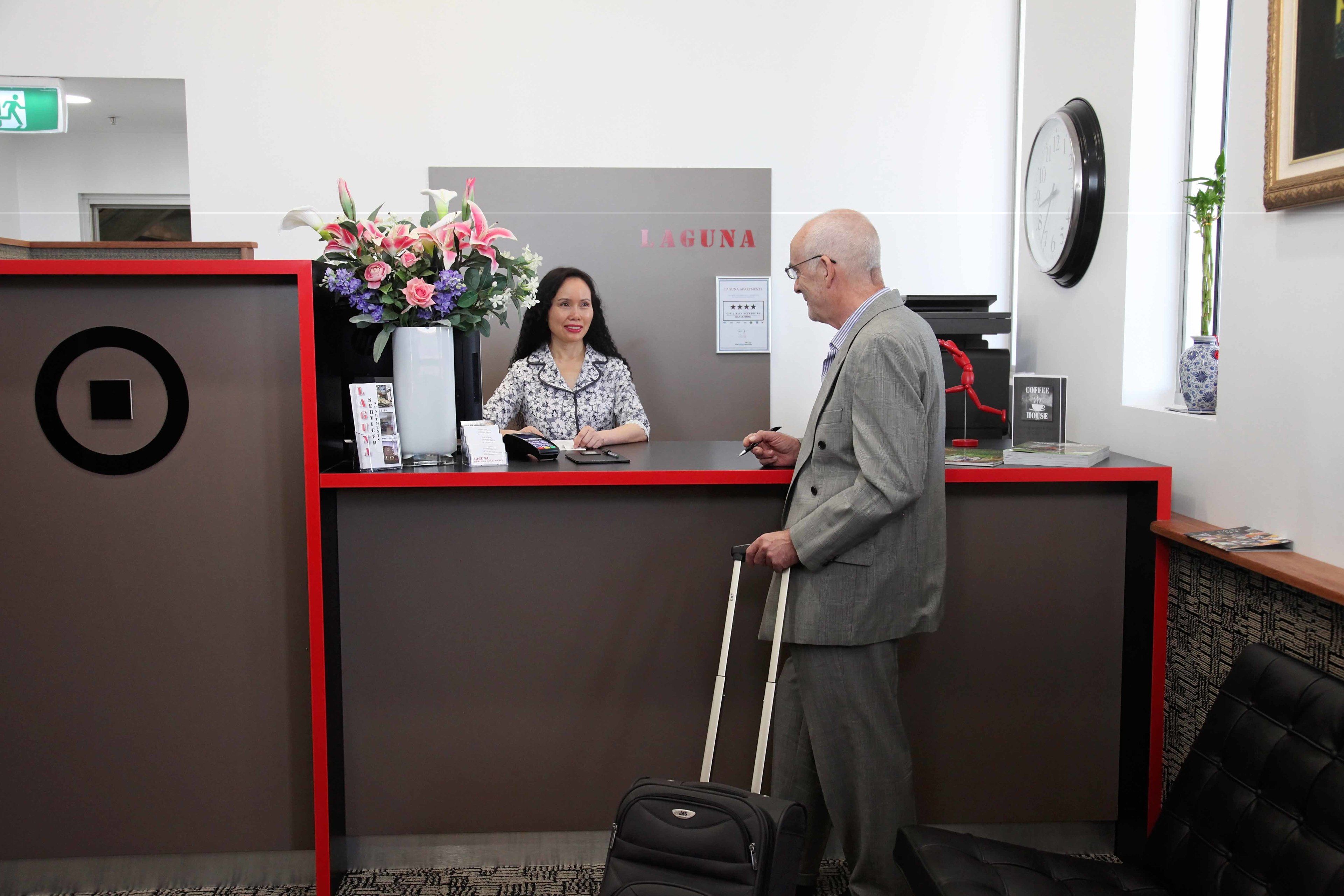A hotel reception desk with a red and black color scheme, a clock, and a framed picture on the wall.