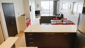 A compact kitchen with a dining area, a sofa, and a TV. - Laguna Apartments (Toowoomba)