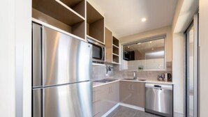 A modern kitchen with stainless steel appliances, a dishwasher, and a large window providing natural light. - Laguna Apartments (Toowoomba)