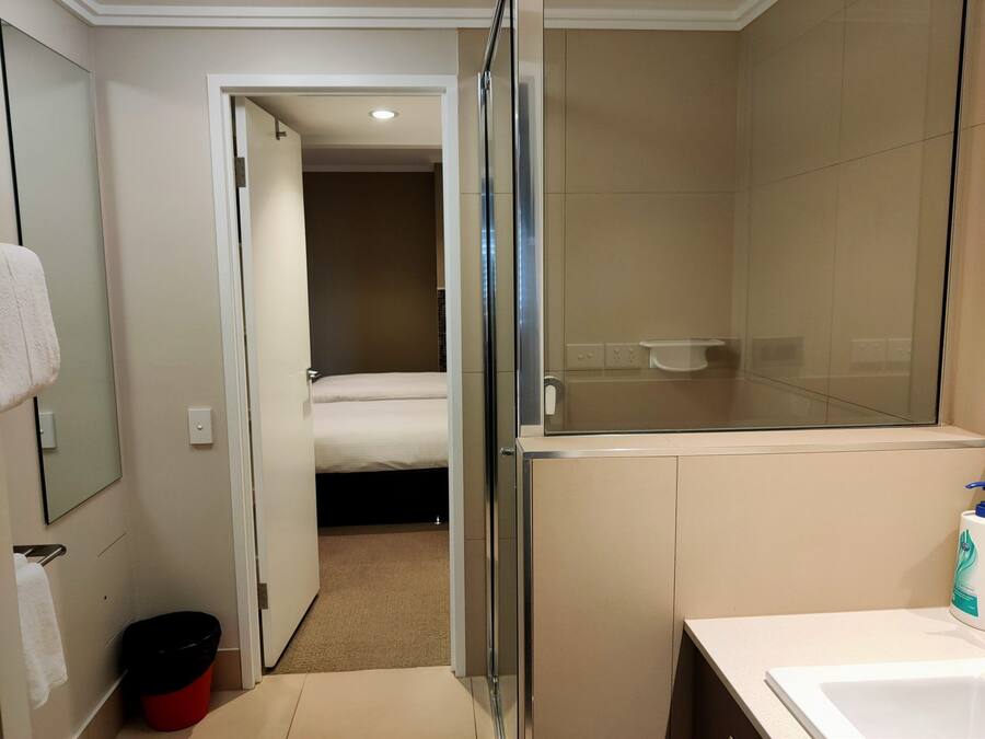 A hotel bathroom with a shower, a sink, and a mirror.