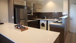 A modern kitchen with a stainless steel refrigerator, built-in oven, microwave, and dishwasher. - Laguna Apartments (Toowoomba)