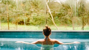 A person in a swimming pool with a view of trees and a fence. - Hepburn Spa Retreat (Hepburn Springs)