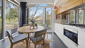 A modern kitchen with a large island, white cabinetry, and a built-in oven. - Hepburn Spa Retreat (Hepburn Springs)