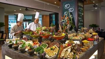 A buffet with various dishes and a chef in the background.