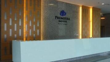 A reception area with a modern design, featuring a prominent logo and the name "Premiera Hotel Kuala Lumpur" on a textured wall.