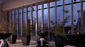 A rooftop terrace with large windows offering a city view, featuring tables with black tablecloths and potted plants. - Premiera Hotel Kuala Lumpur (Kuala Lumpur)