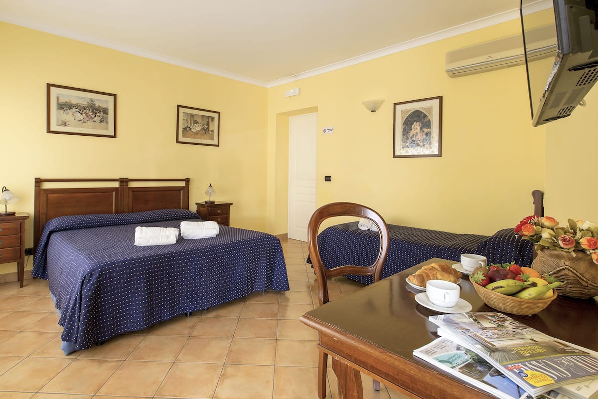 Habitación de hotel con dos camas, una mesa de comedor y alimentos para el desayuno, además de una silla.