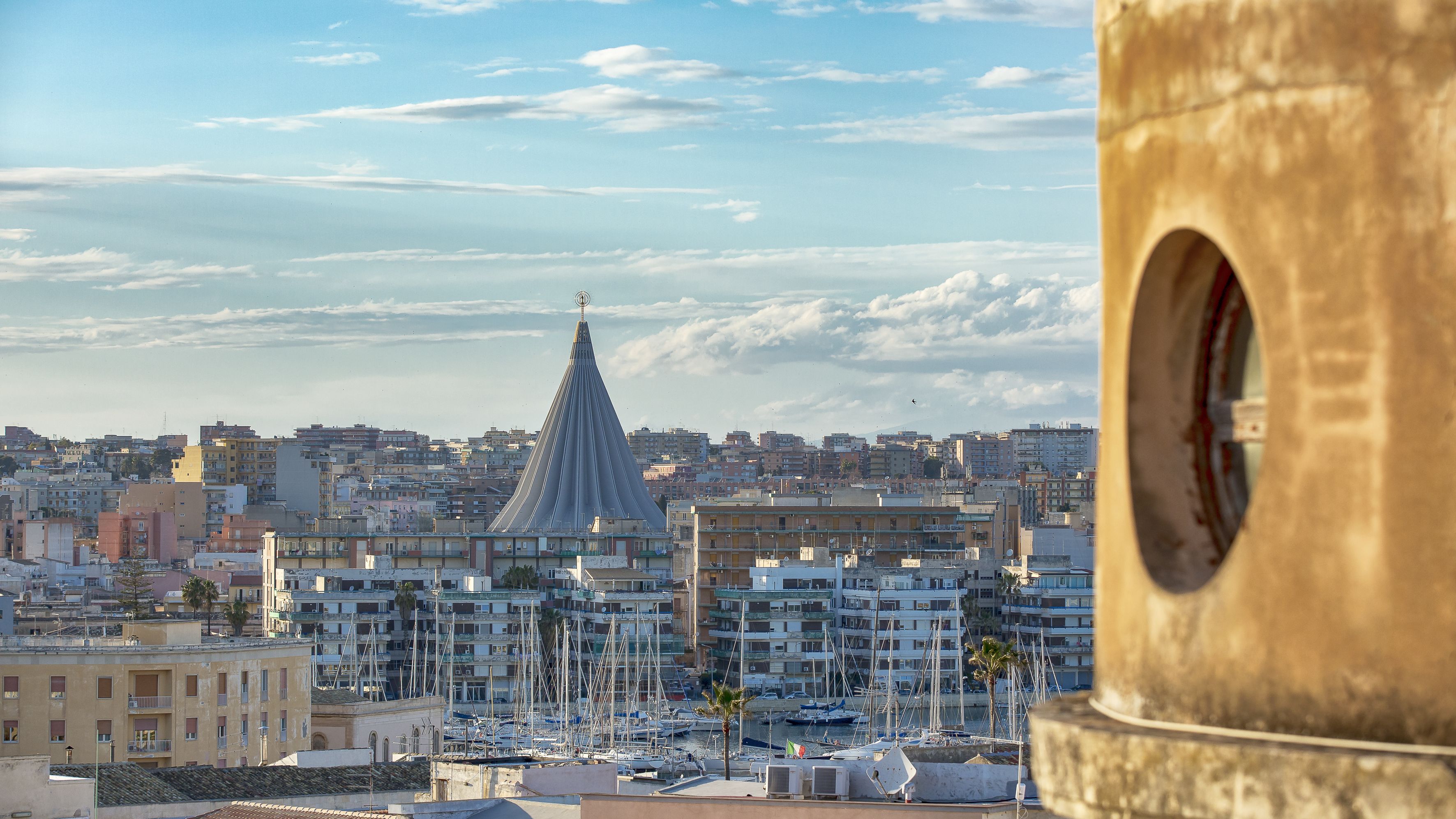 A cityscape with a prominent tower, a marina with boats, and a clear sky.