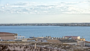 A coastal view with a marina, buildings with tiled roofs, and a distant cityscape. - Bed & Breakfast Armonia (Syracuse)