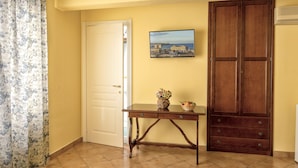 A room with a closed door, a wooden cabinet, a small table with a vase and a basket, and a framed picture on the wall. - Bed & Breakfast Armonia (Syracuse)