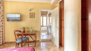 A room with a bed, a wooden table with a chair, a TV, and a bathroom visible through an open door. - Bed & Breakfast Armonia (Syracuse)