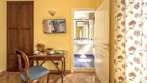 A dining area with a wooden table, a chair, a vase with flowers, and a wall-mounted painting. - Bed & Breakfast Armonia (Syracuse)