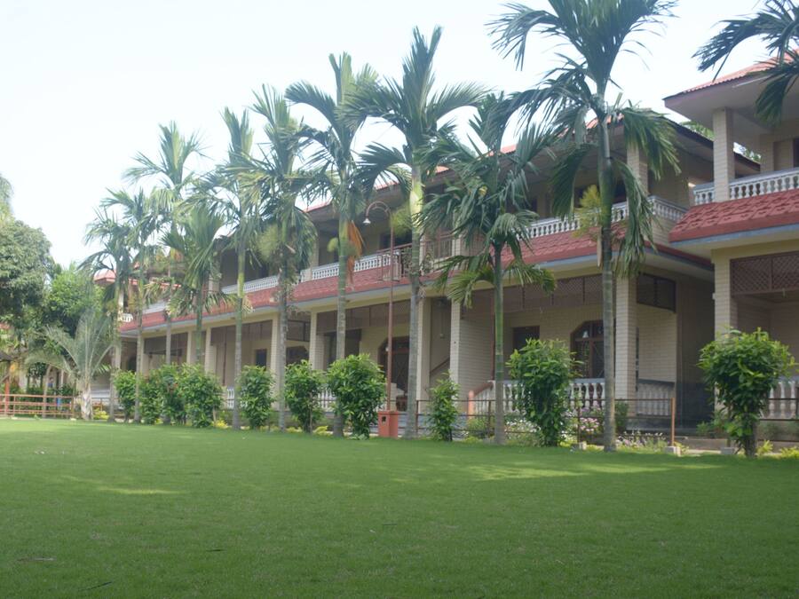 A hotel with multiple-story buildings, a well-maintained lawn, and palm trees.