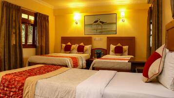 A hotel room with two beds, each with a red and white pillow, a nightstand, a lamp, and a painting of birds on the wall.