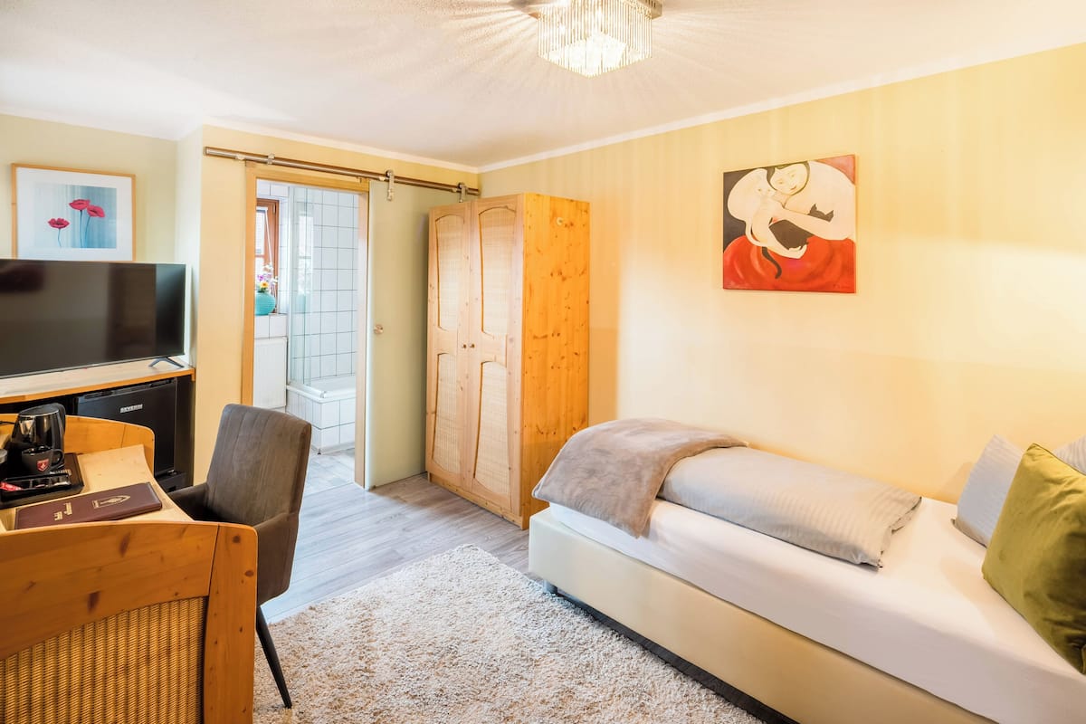 Een moderne woonkamer met een bank, televisie en een houten garderobe.