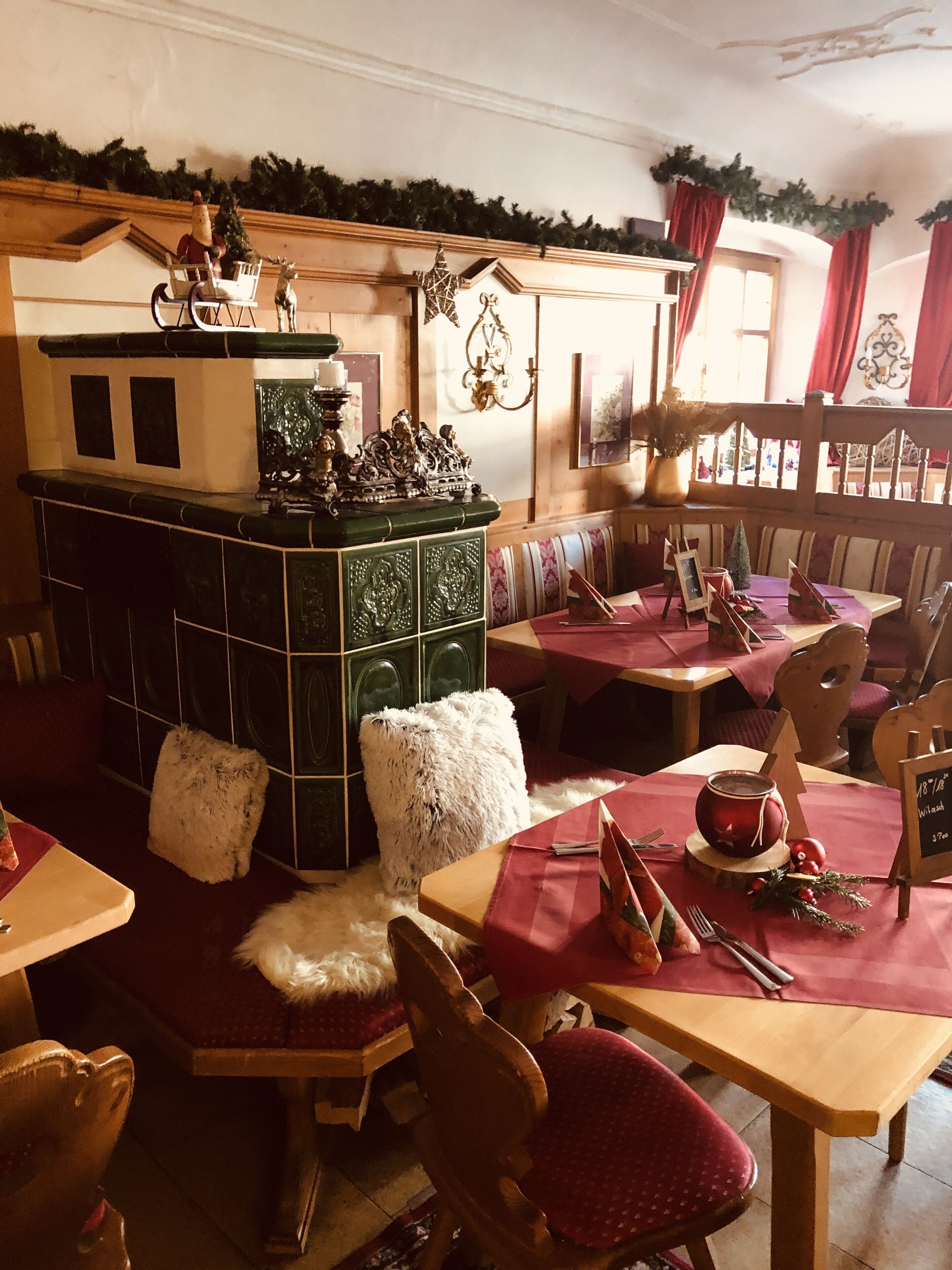 A cozy restaurant interior with wooden furniture, a green bar area, and festive decorations.