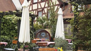 A courtyard with outdoor seating, including tables and chairs, surrounded by a traditional half-timbered building.