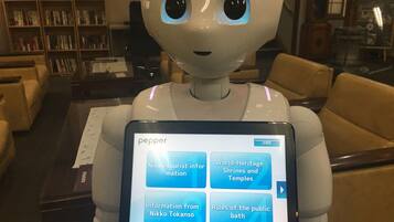 Un robot con una pantalla que muestra información sobre atracciones turísticas y normas para baños públicos.