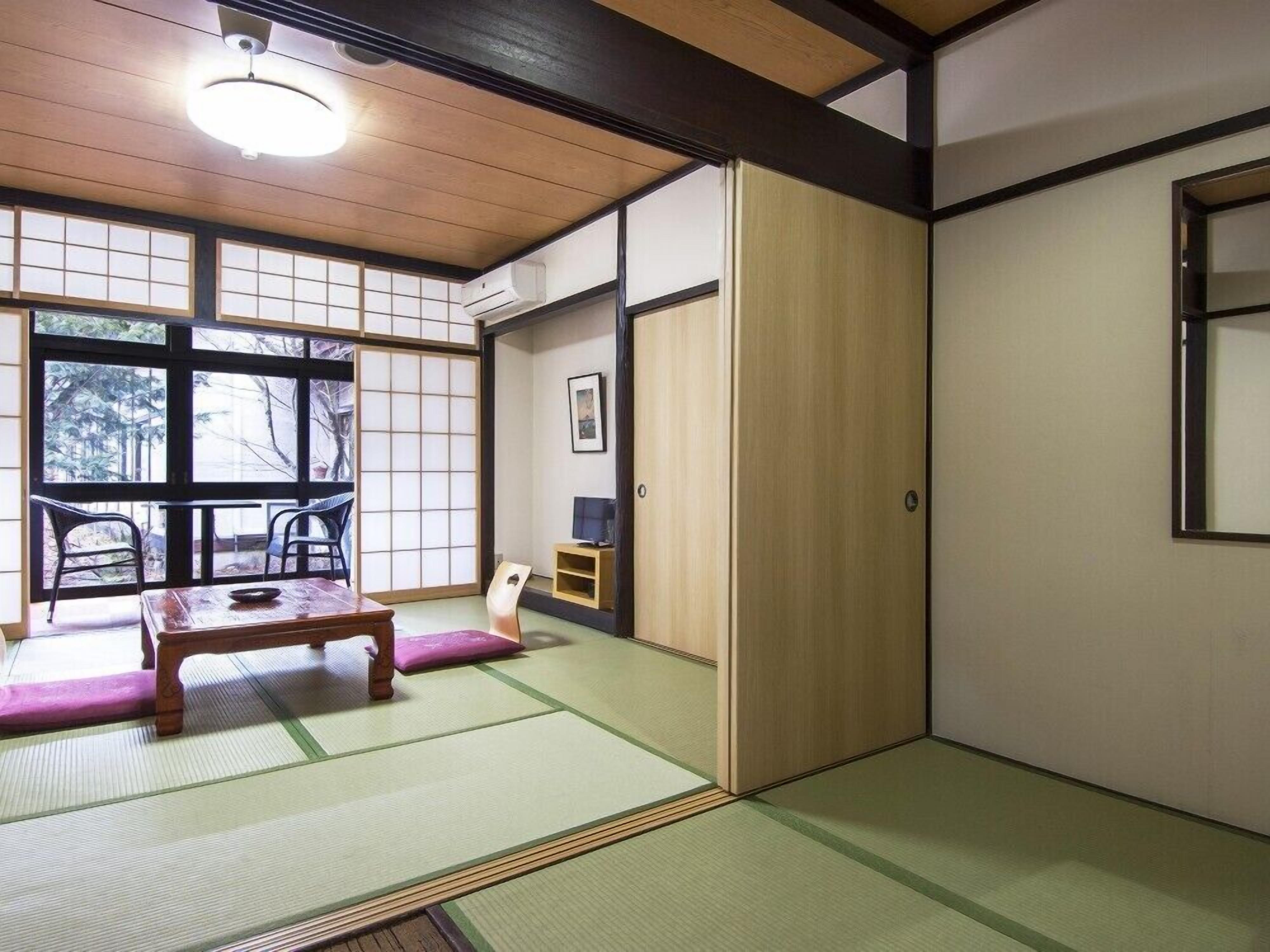 A traditional Japanese room with tatami flooring, a low table, and sliding doors.