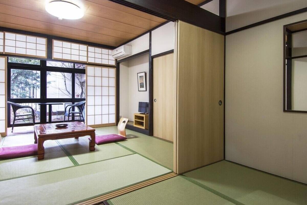 Et traditionelt japansk rum med tatamimåtter, et lavt bord og skydedøre.