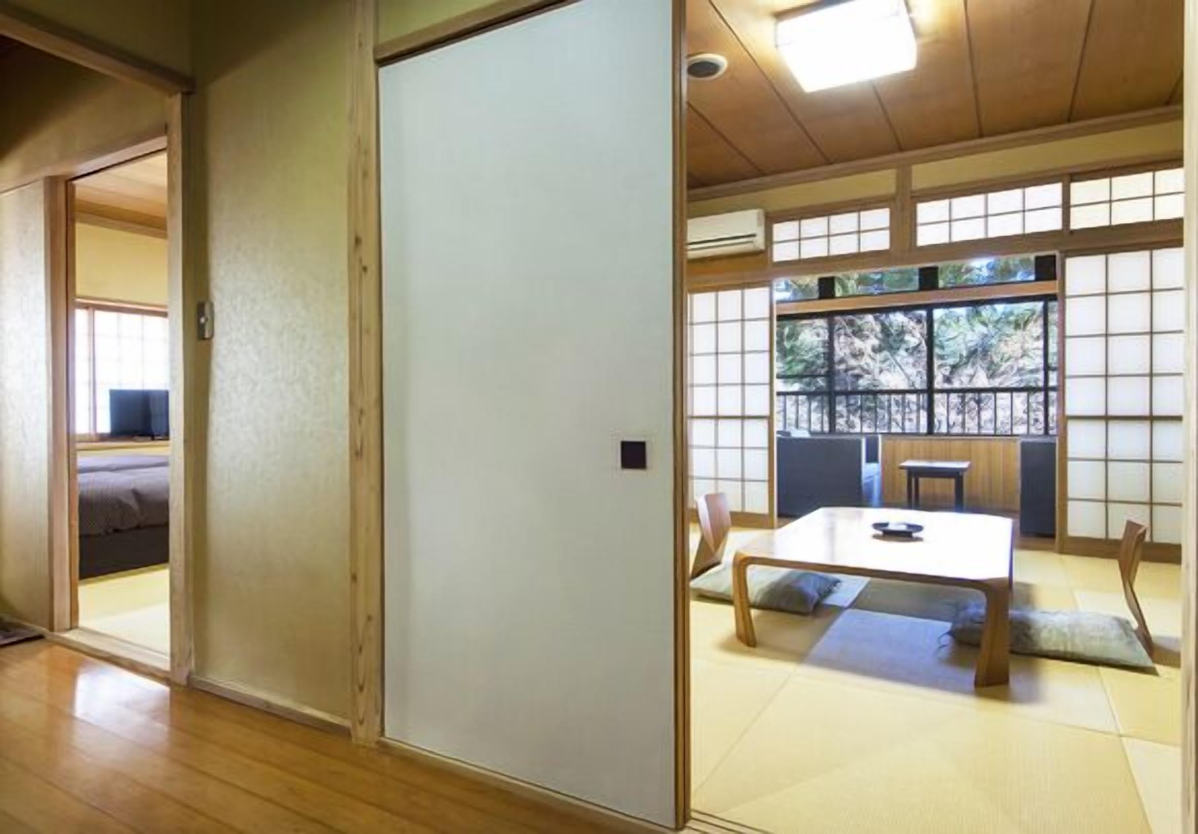 Una habitación japonesa tradicional con suelo de tatami, puertas correderas y una baja mesa con cojines.