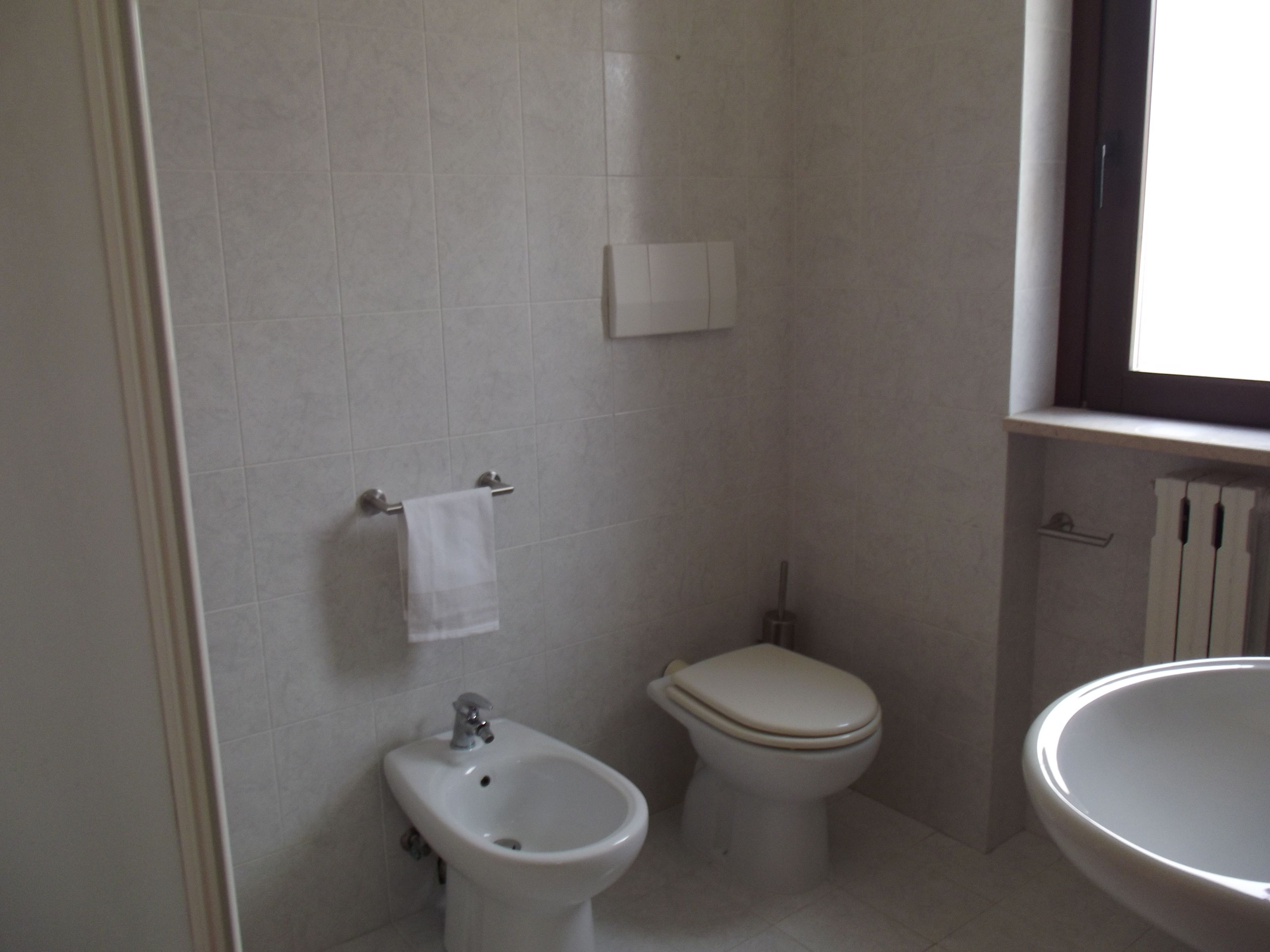 A bathroom with a bidet, toilet, and sink.