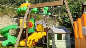 A playground with a slide, climbing structures, and a small house.