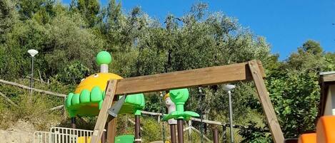 Un parque infantil con un tobogán, estructuras para escalar y una casita.