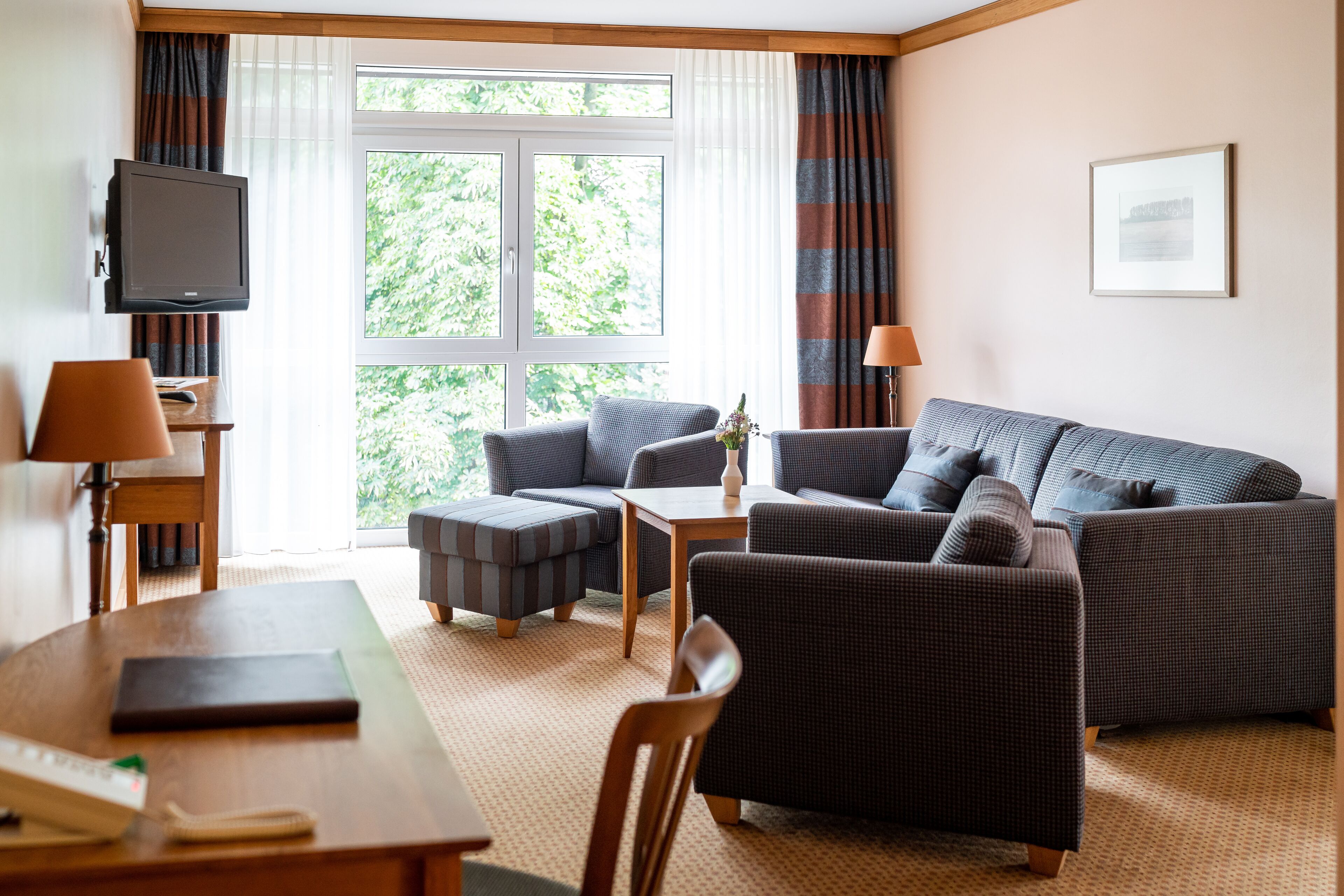 Moderni hotellihuone, jossa on sohva, nojatuoli ja pieni pöytä.