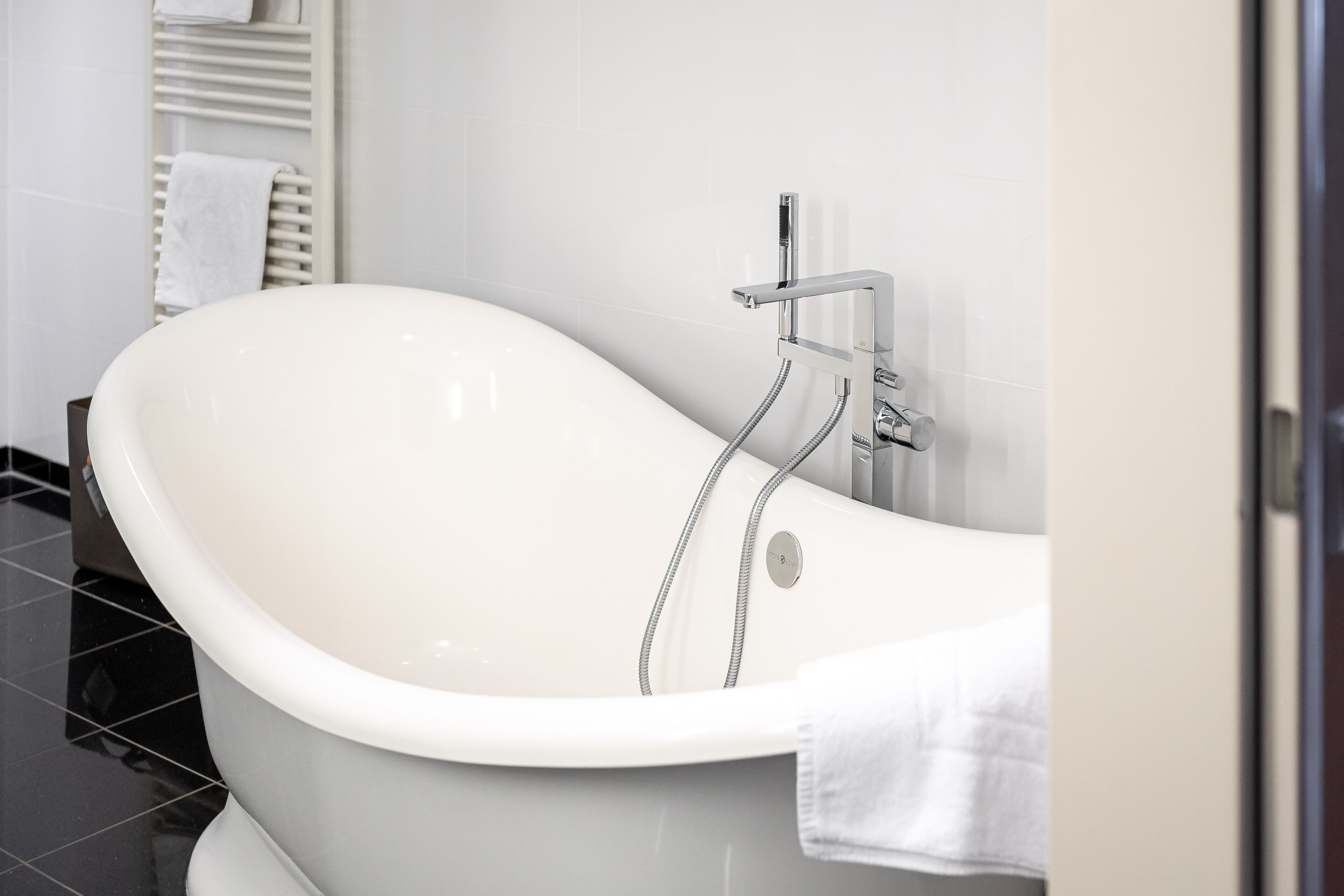 A modern bathroom with a freestanding bathtub, a towel rack, and a toilet.