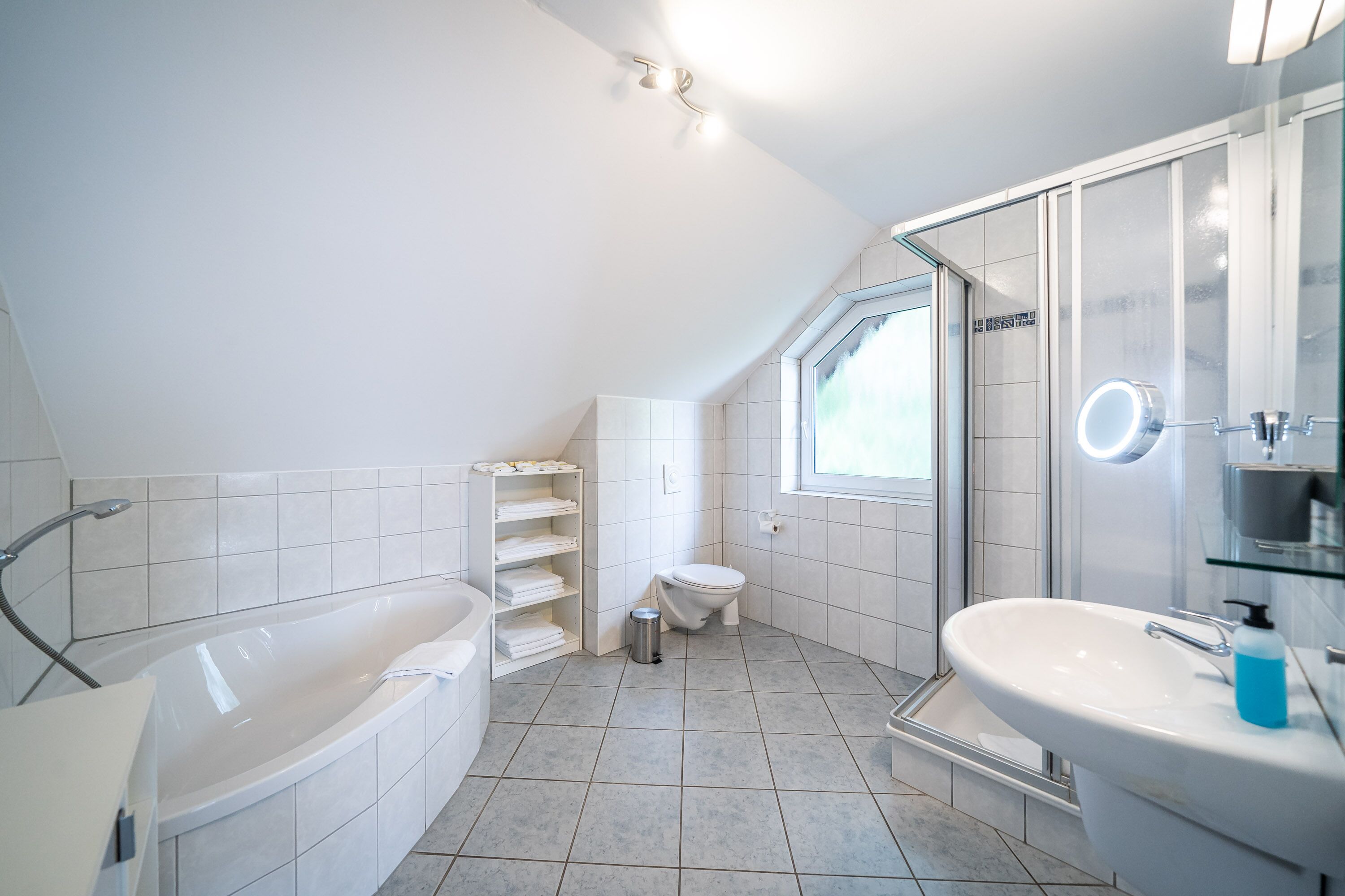 Een moderne badkamer met een vrijstaand bad, een douche met glazen wanden en een wit wastafelmeubel.