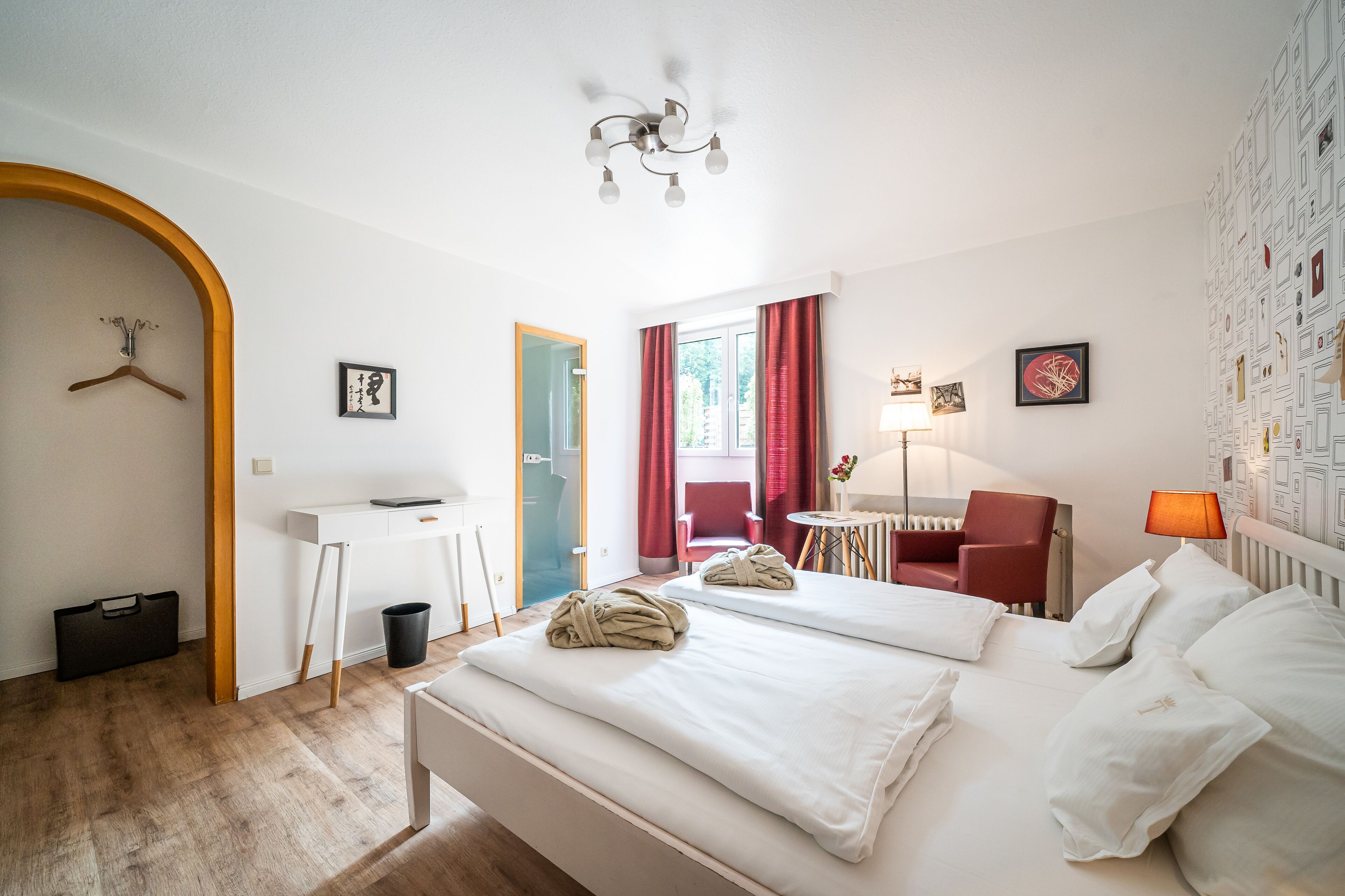 A hotel room with a bed, a desk, a chair, a lamp, and a wardrobe.