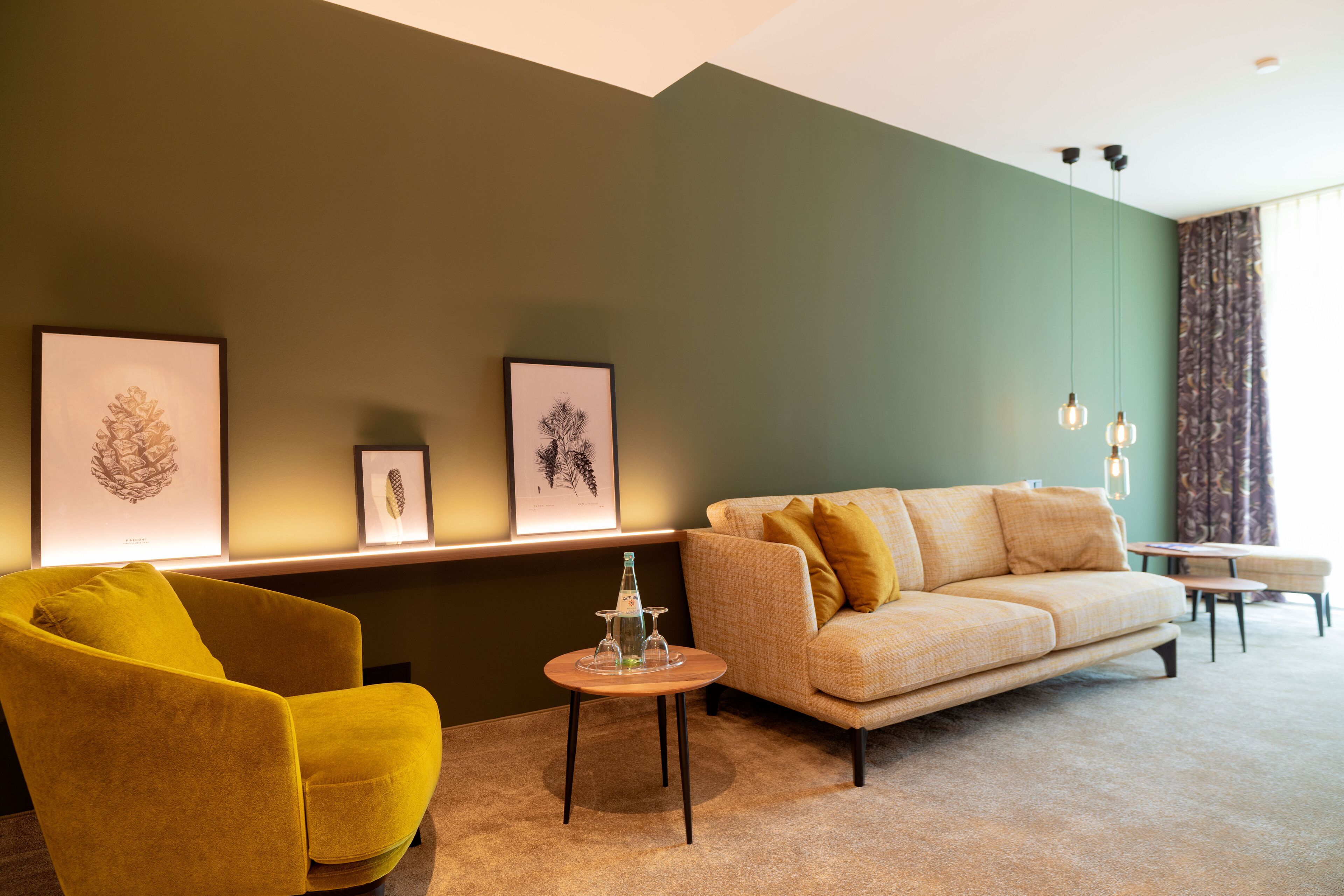 Un salon moderne avec un canapé, un fauteuil et une petite table sur laquelle se trouvent une bouteille et des verres.