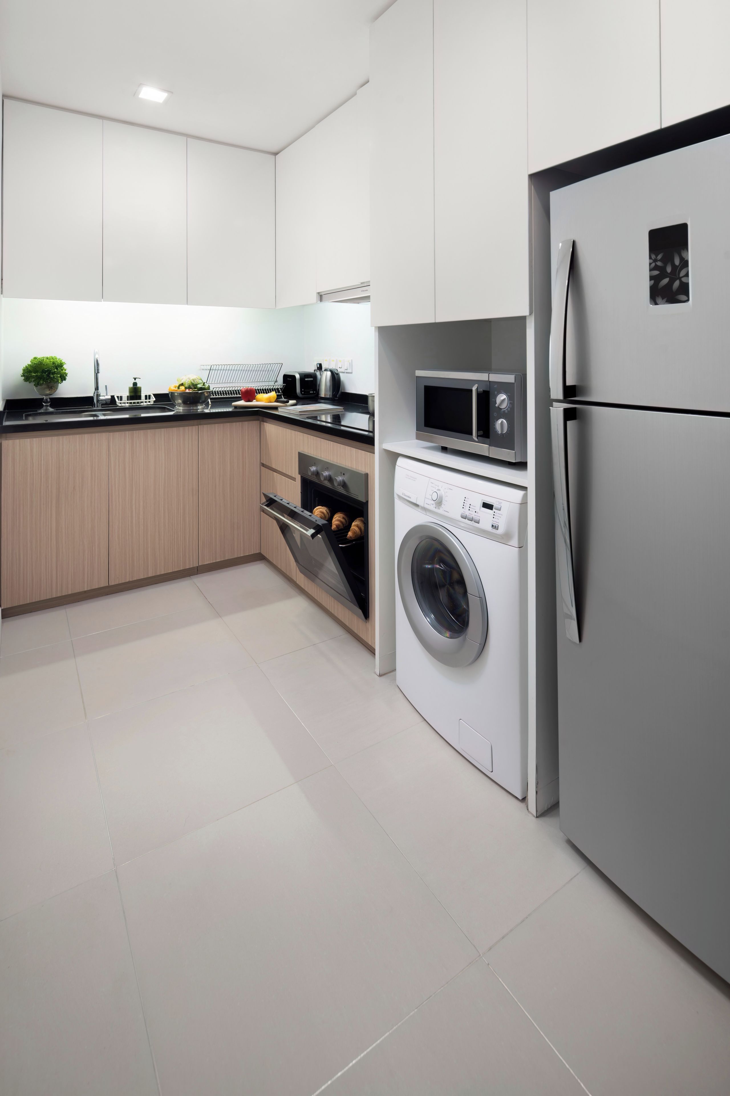 A modern kitchen with stainless steel appliances, wooden cabinets, and a tiled floor.