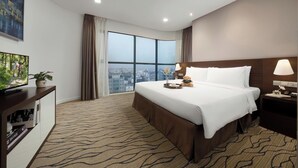 Habitación de hotel con una cama grande, televisión, escritorio y vistas a la ciudad.
