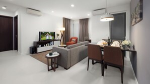 Una sala de estar moderna con un sofá, una mesa de comedor, sillas, un televisor y una lámpara.
