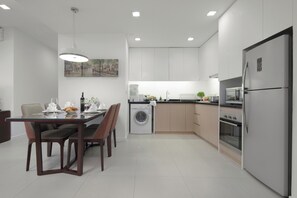 A modern kitchen with a dining area, including a table set for two, a washing machine, and a refrigerator. - Somerset Central TD Hai Phong City (Hai Phong)
