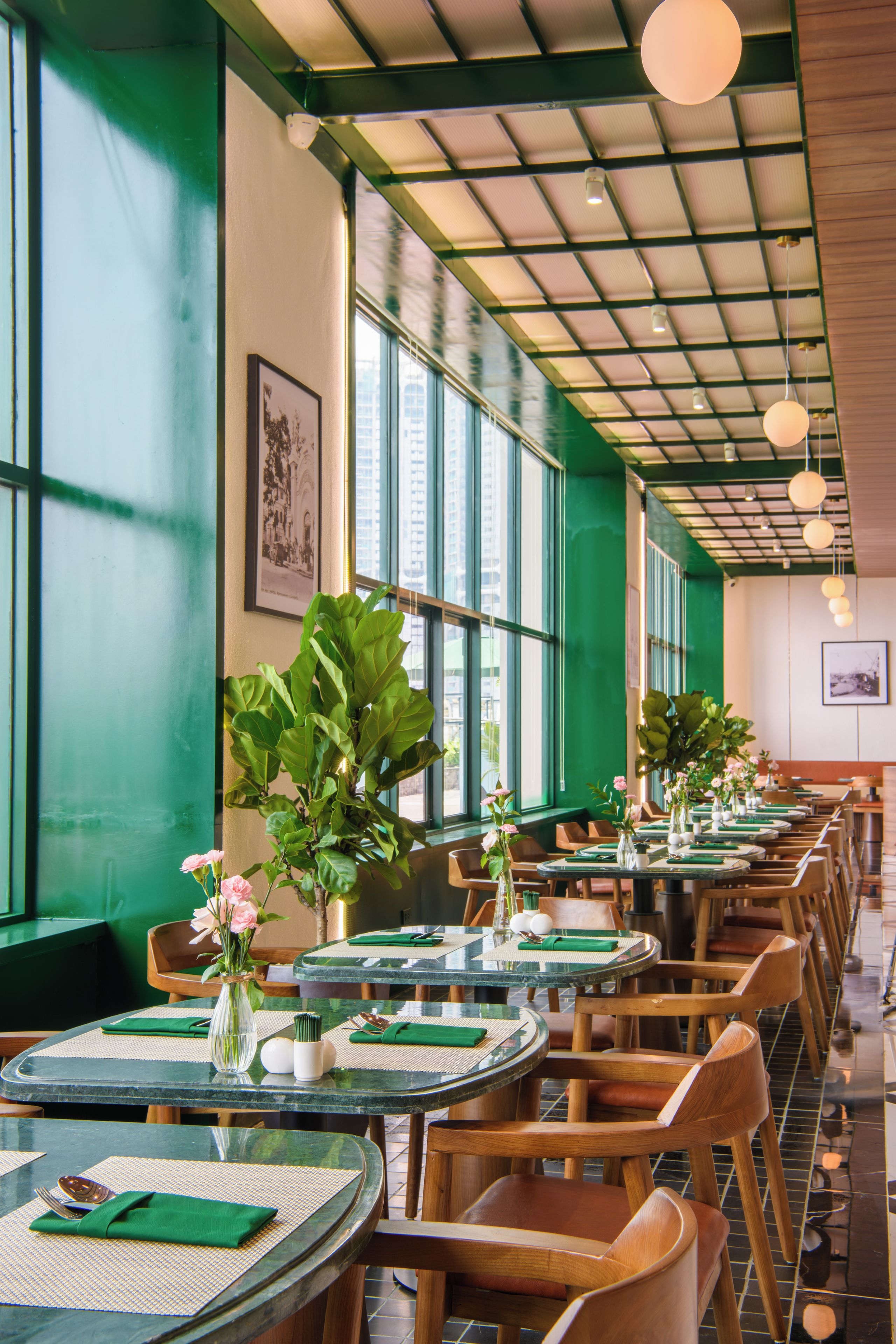 L’intérieur d’un restaurant avec des tables rondes, des chaises et des murs verts.
