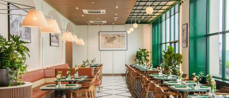 Un interior de restaurante con mesas altas, sillas y un amplio ventanal.